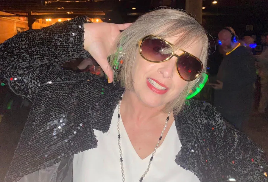 Guest in a sequined jacket and sunglasses dancing in green-lit headsets